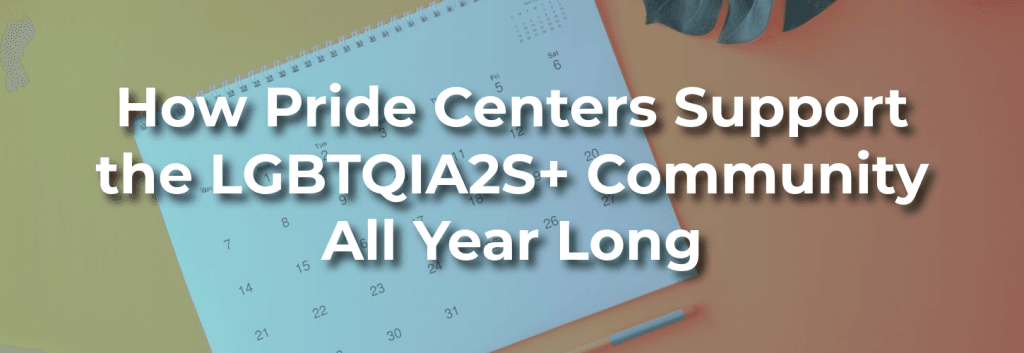 Overhead view of a desk with a monthly calendar, pen, and plant, with overlay text: “How Pride Centers Support the LGBTQIA2S+ Community All Year Long.”