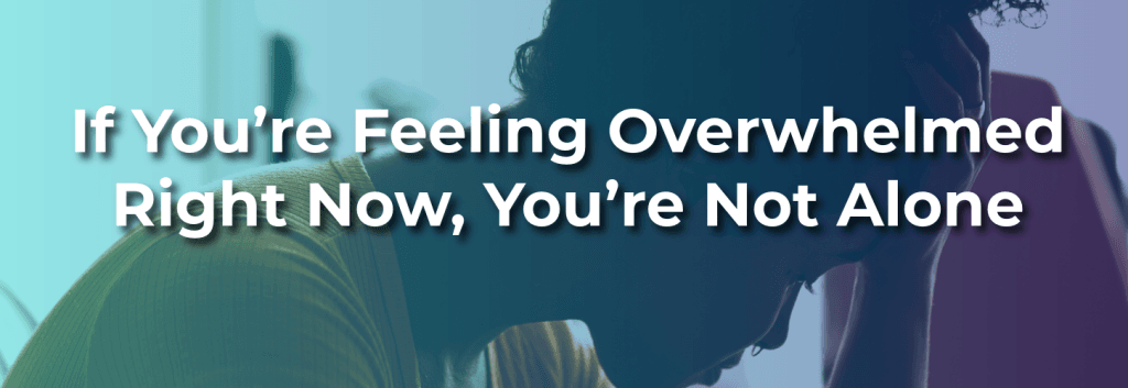 A person sitting with their head resting on their hand, appearing overwhelmed or distressed, with overlaid text reading “If You’re Feeling Overwhelmed Right Now, You’re Not Alone.”